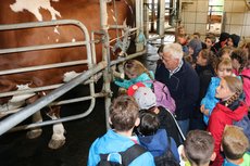 Bauer erklärt Kindern den Melkstand